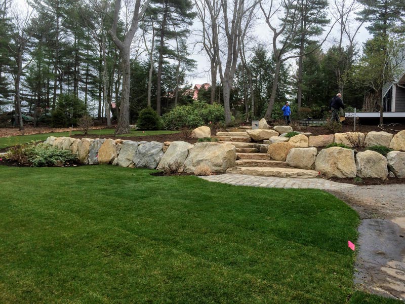 Large stone wall, stairs, and green lawn.